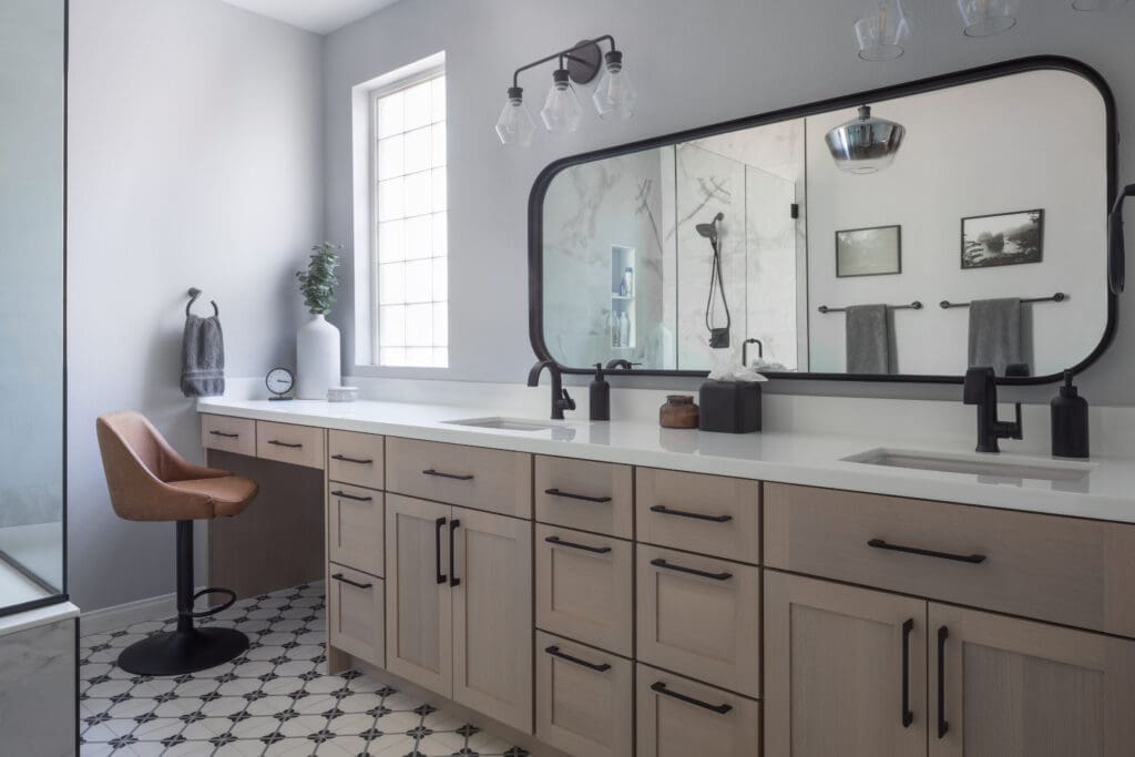 The master bathroom features a long vanity and makeup station with custom cabinets by Plato Woodwork. Designed by Stacie Young of Innovative Kitchens & Interiors.